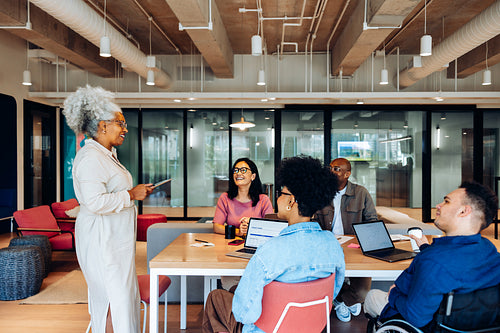 Senior woman leads a casual team meeting in modern office
