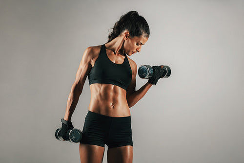 Woman with toned muscular body lifting weights