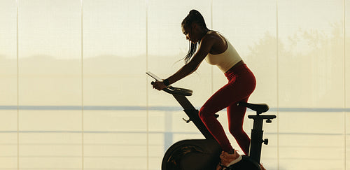 Woman engaging in an online fitness class with a stationary bike