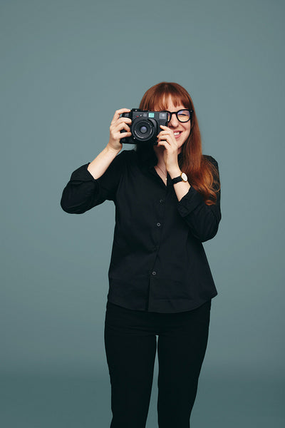 Smiling photographer taking a picture on her digital camera
