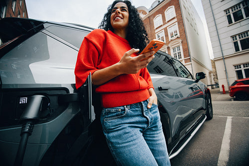 Young woman charges electric car using fast charger in city