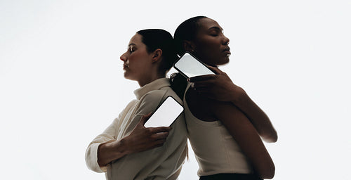 Two women back-to-back holding smartphones for communication and mockup concepts