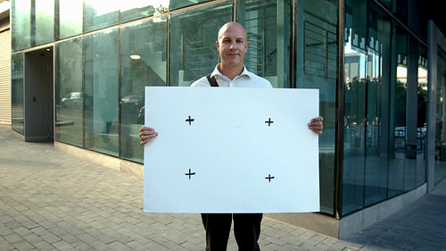 Businessman holding empty banner outside office building