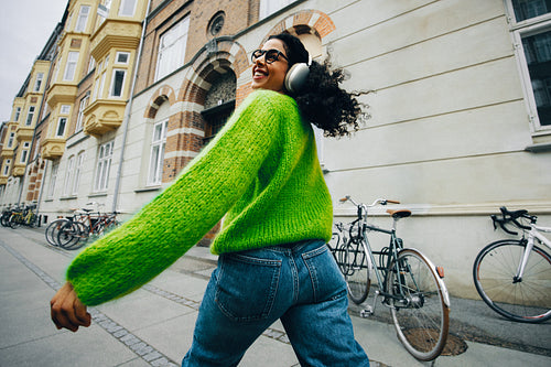 On a lively street, the woman walks with headphones and music in the city