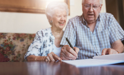 Senior couple signing documents at home