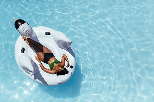 Woman relaxing on inflatable swan floating in pool
