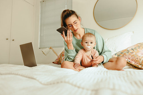 Single mom taking a phone call while sitting with her baby