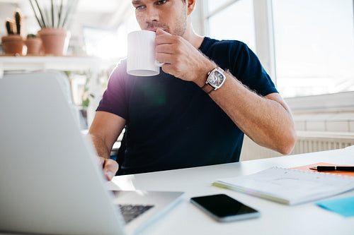 Businessman drinking coffee and working on laptop