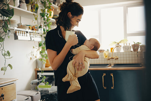 Mother bonding with baby at home with a cup of coffee