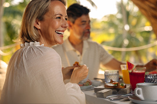 Mature couple enjoying breakfast at a tropical resort with bright sunshine