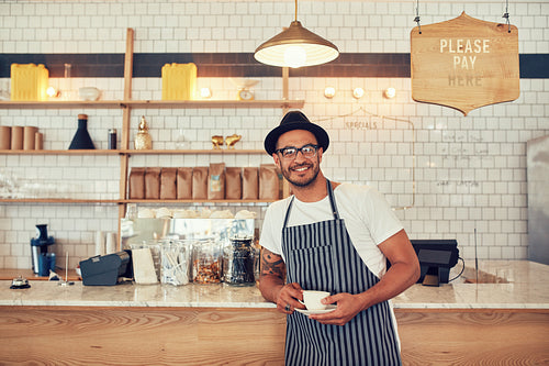 Barista standing at bar counter and smiling at camera