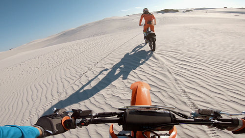 Motorcyclist racing behind his competitor in a desert