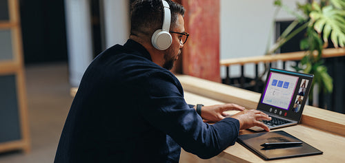 Male designer having a video conference with his team in a coworking office