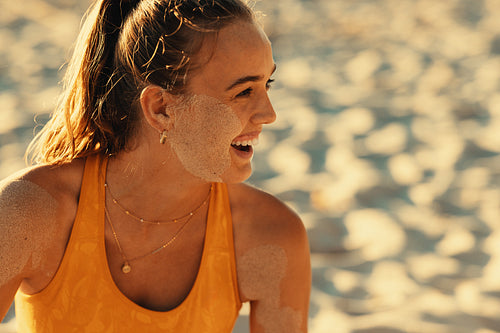 Happy young athlete resting on sandy beach after beach volleyball game