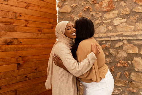 Two female friends greeting each other with a hug in a cafe