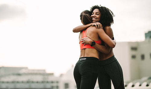 Smiling athlete giving a hug to her friend during workout