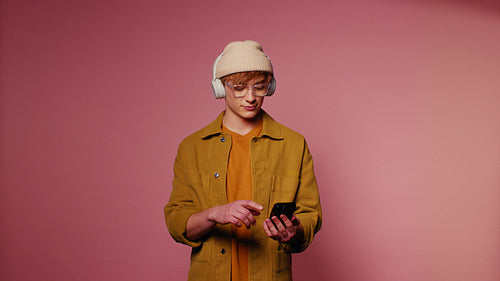 Young man picking a song on his phone and dancing with headphones