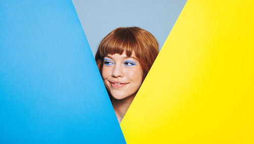 Happy woman with ginger hair and blue eye shadow standing behind colour placards