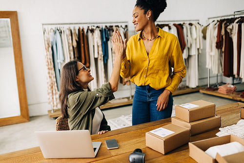 Ecommerce success: Female online store owners giving each other a high five in celebration