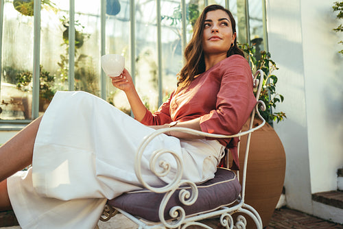 Thoughful tourist woman holding a cup of coffee outdoors