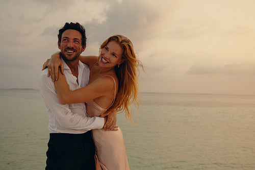 Radiant sunset embrace: Newlyweds basking in love on a tropical beach