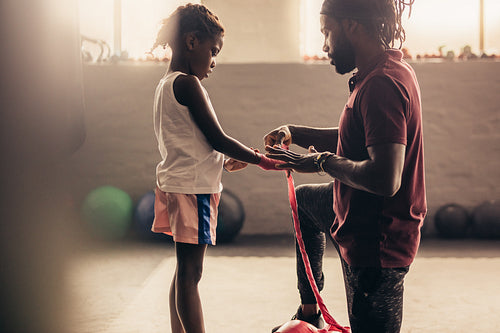 Boxing trainer wrapping hands of a kid with bandage