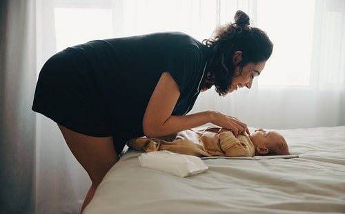 Mother plays with baby on the bed