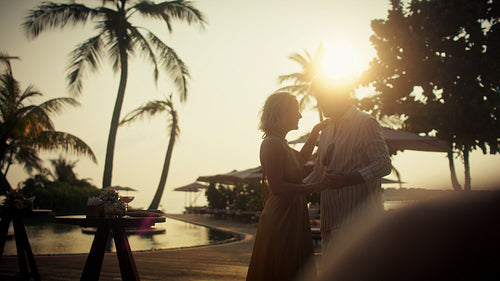 A honeymoon couple dances together at a beautiful tropical resort during golden hour sunset