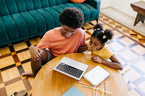 Children studying together at home, using a laptop for online learning