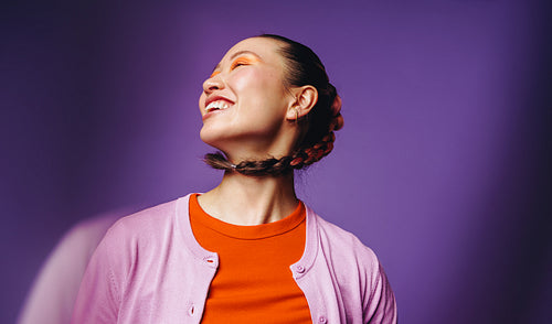 Asian woman with vibrant makeup smiling in modern studio portrait