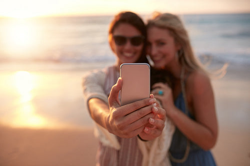 Female friends taking selfie with beach sunset