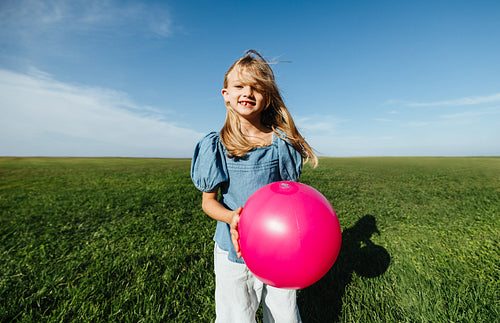 Girl with pink ball in open field