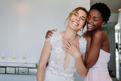 Cheerful bride and bridesmaid on the wedding day