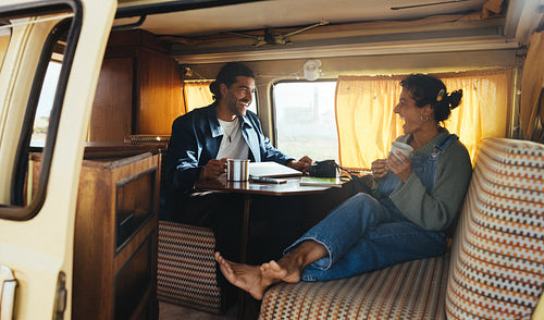 Couple enjoying coffee and conversation inside a cozy camper van