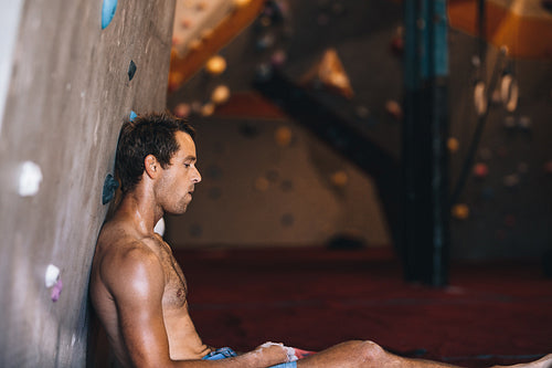 Man at a wall climbing gym taking rest
