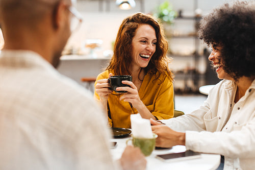 Happy young people chatting and having coffee on a friends date