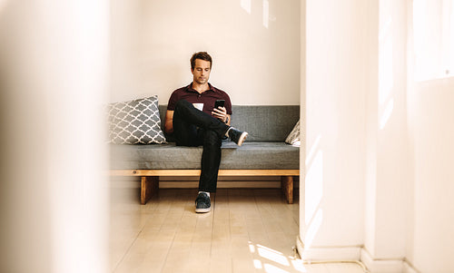 Man looking at mobile phone sitting at home