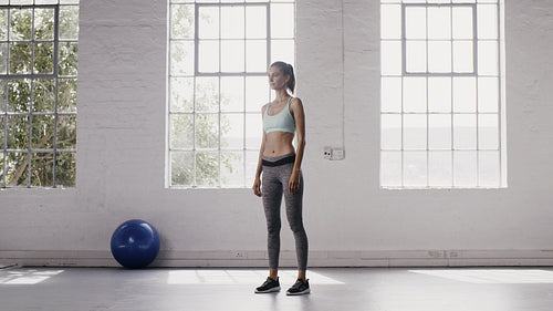Woman exercising jumping squats in fitness studio