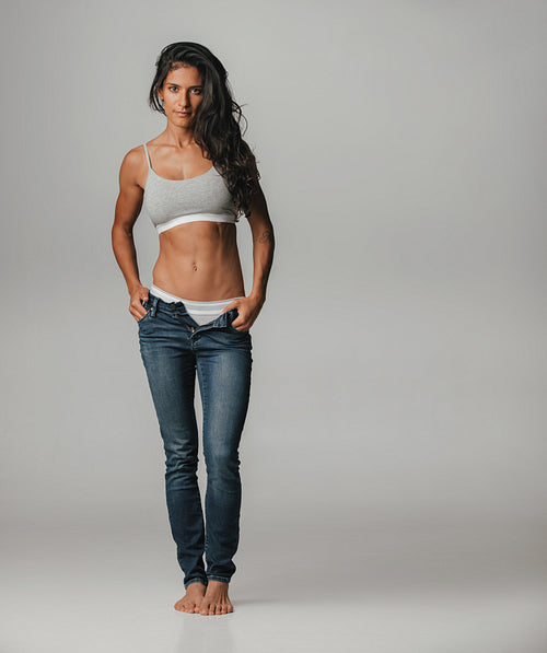 Barefoot young woman loosening pants buttons