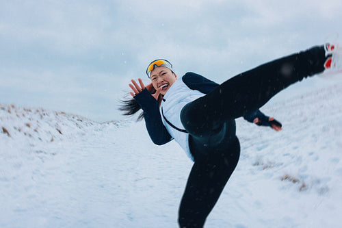 Winter finds a woman training in the snow with a playful high kick outdoors
