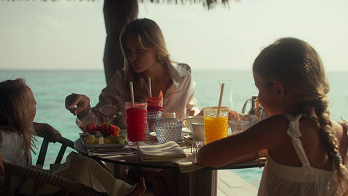 Mother and children enjoying a luxury breakfast at an overwater villa on an island resort