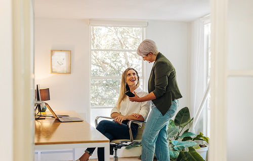 Happy businesswoman showing her colleague her smartphone screen