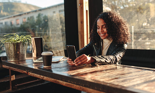 Woman sitting in a coffee shop looking at mobile phone