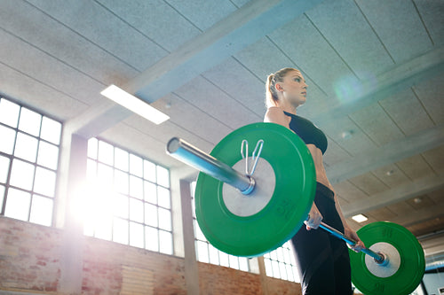 Fit female athlete lifting weights in gym