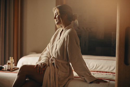 Happy woman relaxing at spa hotel in bathrobe enjoying facial treatment and relaxation