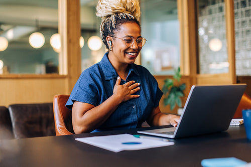 Smiling woman enjoying a video call with a laptop in a cozy office