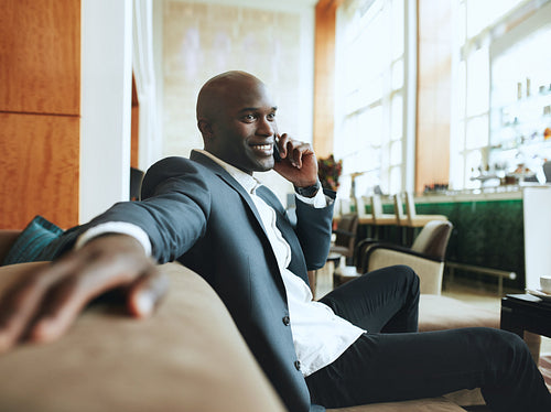 Happy young businessman waiting at hotel lobby making a phone call