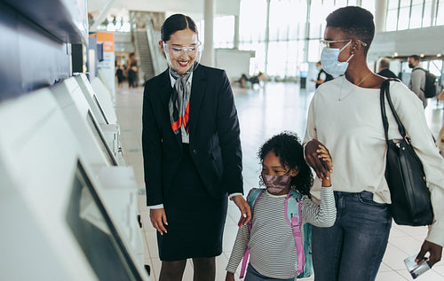 Family at airport with airlines staff during pandemic