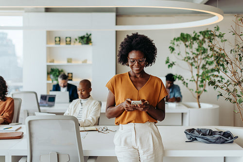 Happy businesswoman using smartphone in a creative modern office