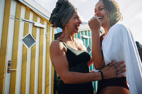 Women enjoy wellness recovery with towel outdoors after swim near beach huts in summer